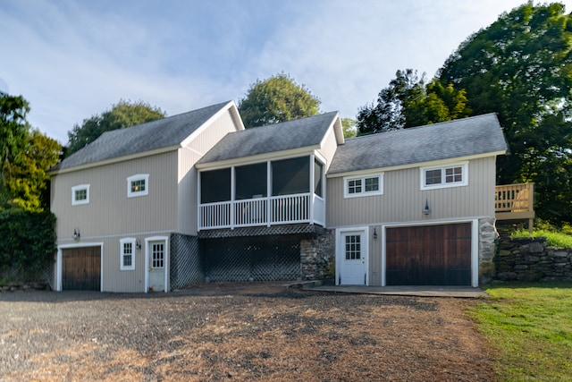 rear view of house featuring a garage and a sunroom