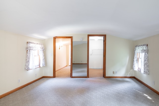 interior space with a closet, light carpet, lofted ceiling, and a walk in closet