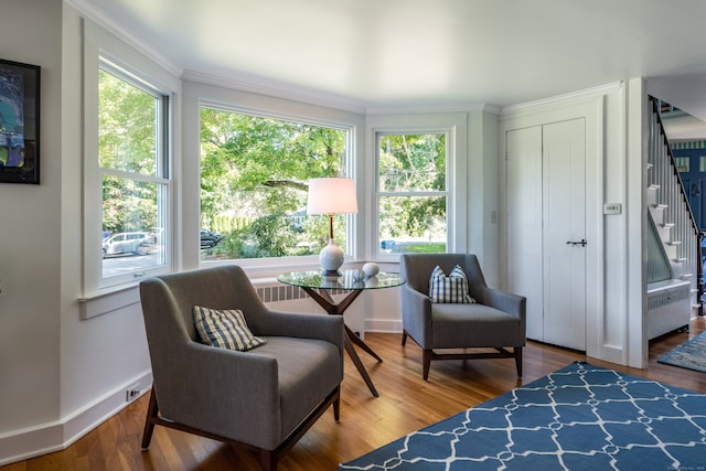 living area featuring ornamental molding, wood-type flooring, and radiator heating unit