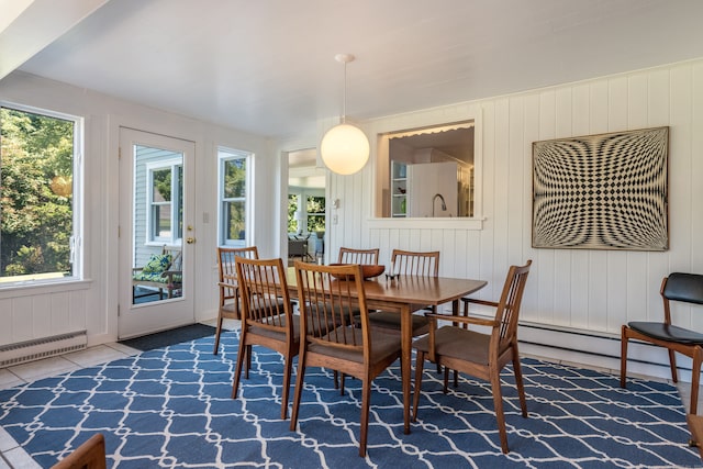 dining room with a baseboard heating unit, wooden walls, and tile patterned flooring