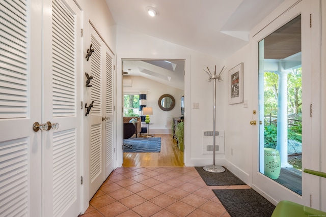 foyer featuring lofted ceiling, heating unit, and light hardwood / wood-style flooring