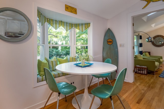 dining space with light wood-type flooring and a skylight