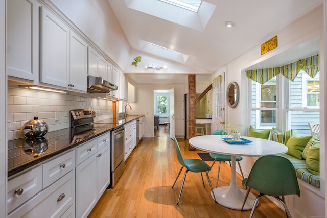 kitchen featuring white cabinets, lofted ceiling with skylight, stainless steel electric stove, light hardwood / wood-style floors, and decorative backsplash