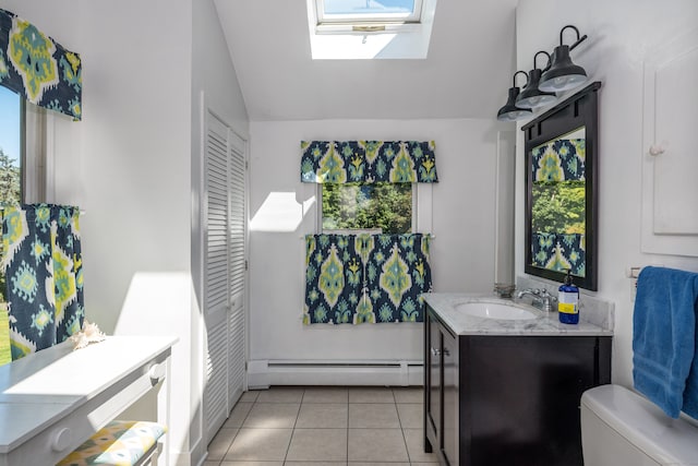 bathroom with toilet, vaulted ceiling with skylight, tile patterned floors, vanity, and baseboard heating