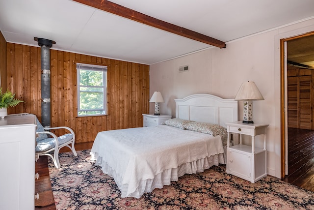 bedroom featuring a wood stove, wood walls, dark hardwood / wood-style floors, and beamed ceiling