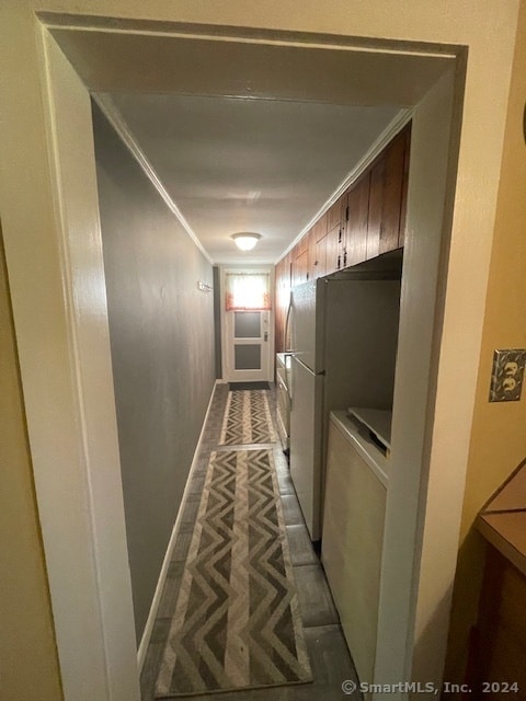 hallway with independent washer and dryer, ornamental molding, and dark tile patterned flooring