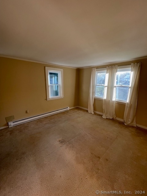 empty room with crown molding, baseboard heating, and light colored carpet