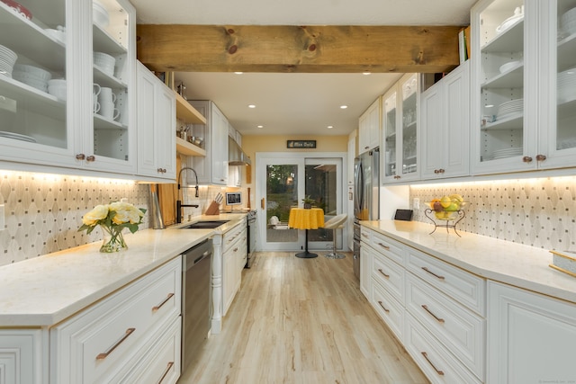 kitchen with appliances with stainless steel finishes, tasteful backsplash, white cabinetry, sink, and light stone counters