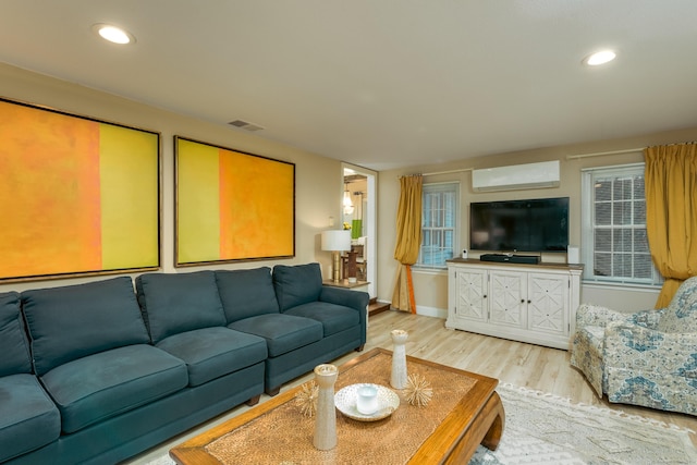 living room featuring light hardwood / wood-style floors and a wall unit AC