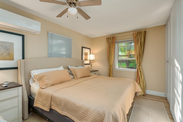 bedroom with light wood-type flooring, a wall mounted air conditioner, and ceiling fan