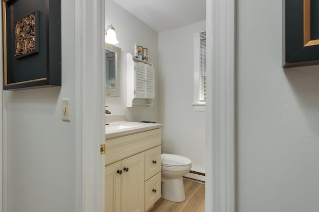 bathroom with baseboard heating, hardwood / wood-style flooring, toilet, and vanity