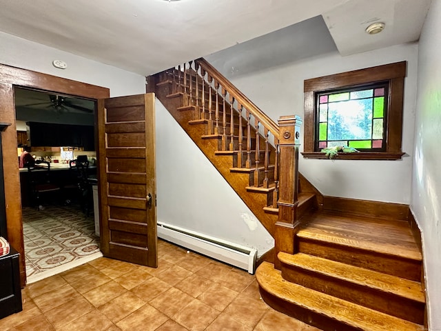 stairway featuring a baseboard heating unit and ceiling fan