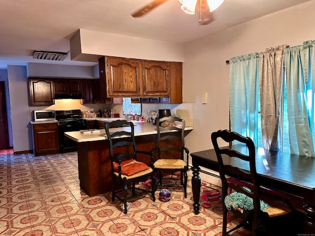 kitchen with black gas stove, ceiling fan, kitchen peninsula, and a breakfast bar area