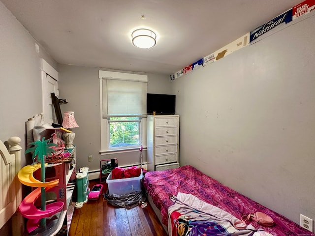 bedroom with a baseboard heating unit and dark hardwood / wood-style flooring