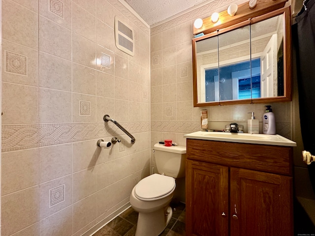 bathroom featuring a textured ceiling, vanity, tile walls, toilet, and tile patterned floors