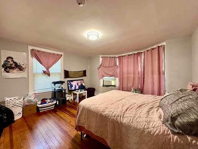 bedroom with cooling unit, a baseboard heating unit, and dark hardwood / wood-style flooring