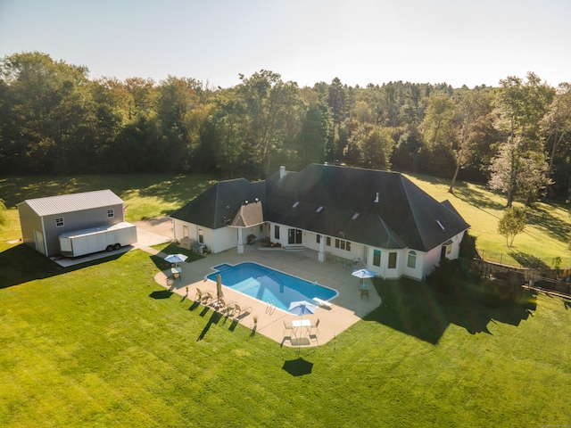 view of swimming pool featuring a diving board, a yard, an outdoor structure, and a patio