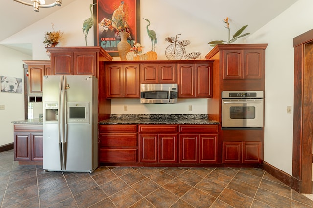 kitchen featuring appliances with stainless steel finishes, dark stone countertops, and vaulted ceiling