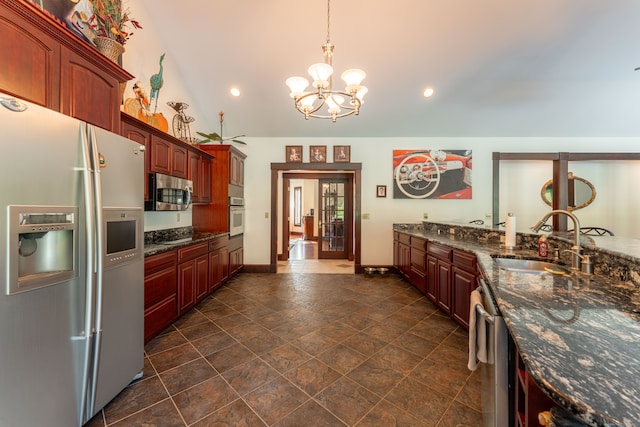 kitchen with dark stone countertops, appliances with stainless steel finishes, an inviting chandelier, and sink