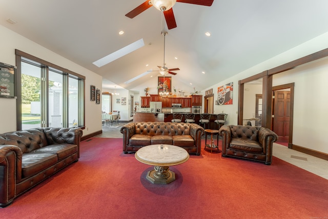 living room featuring high vaulted ceiling, a skylight, ceiling fan, and carpet flooring