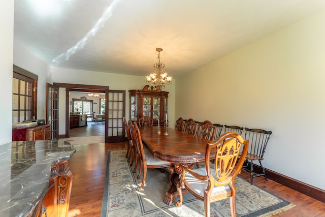 dining area featuring french doors, wood-type flooring, and a chandelier