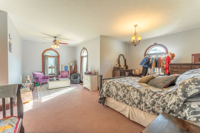 carpeted bedroom with ceiling fan with notable chandelier