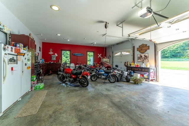 garage with a garage door opener and white refrigerator with ice dispenser