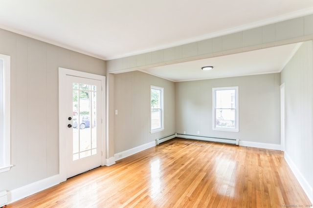 interior space featuring crown molding, a baseboard heating unit, and light hardwood / wood-style floors