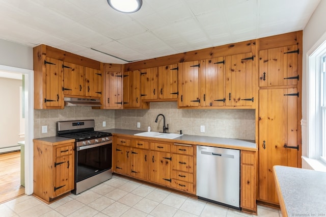 kitchen featuring appliances with stainless steel finishes, light hardwood / wood-style flooring, a baseboard heating unit, tasteful backsplash, and sink