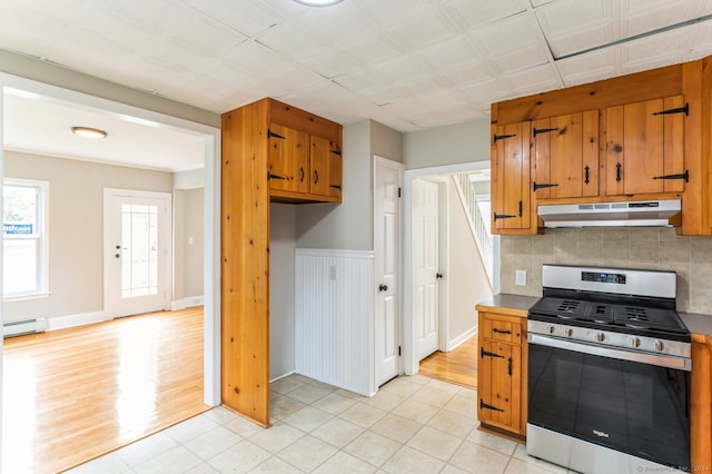 kitchen with light wood-type flooring, a baseboard radiator, tasteful backsplash, and stainless steel gas stove