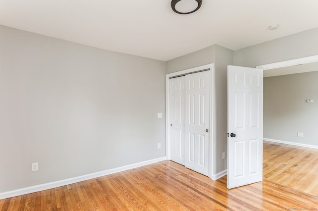 unfurnished bedroom with light wood-type flooring and a closet