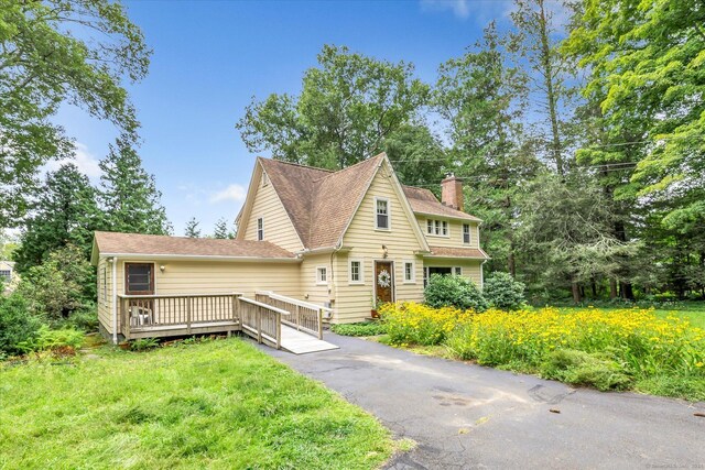 view of front facade with a front lawn and a wooden deck