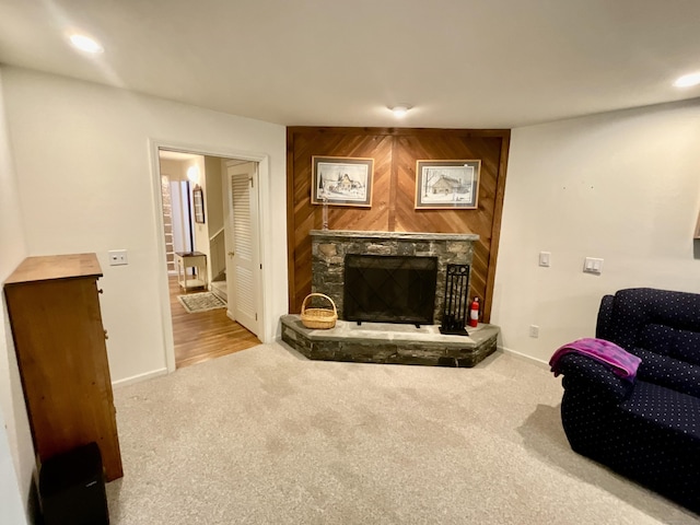 carpeted living room with baseboards, recessed lighting, and a stone fireplace