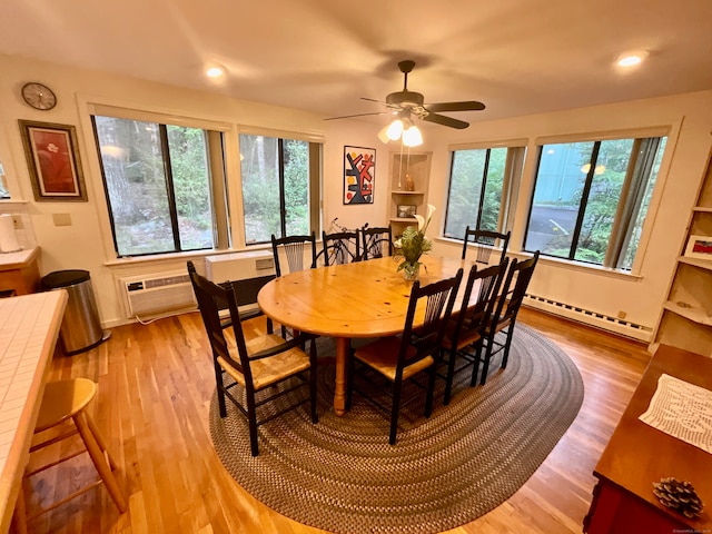 dining room with ceiling fan, light hardwood / wood-style flooring, baseboard heating, and a healthy amount of sunlight