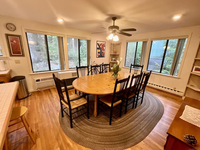 dining area featuring a baseboard heating unit, a ceiling fan, a wall unit AC, and wood finished floors