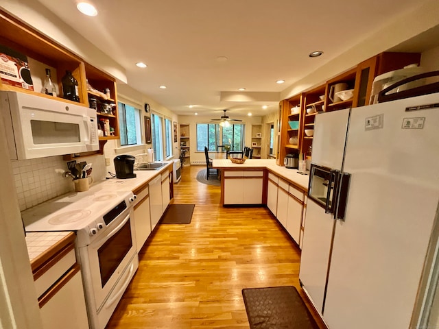 kitchen featuring light wood-type flooring, ceiling fan, decorative backsplash, white cabinets, and white appliances