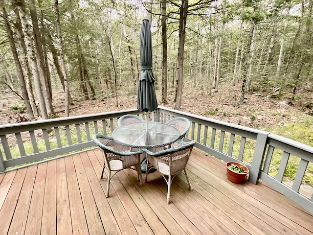 deck featuring outdoor dining area and a view of trees