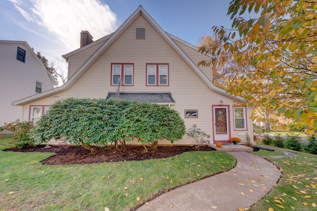 view of front of home with a front yard and a chimney