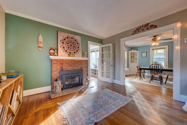 living room featuring plenty of natural light, ornamental molding, baseboards, and wood finished floors