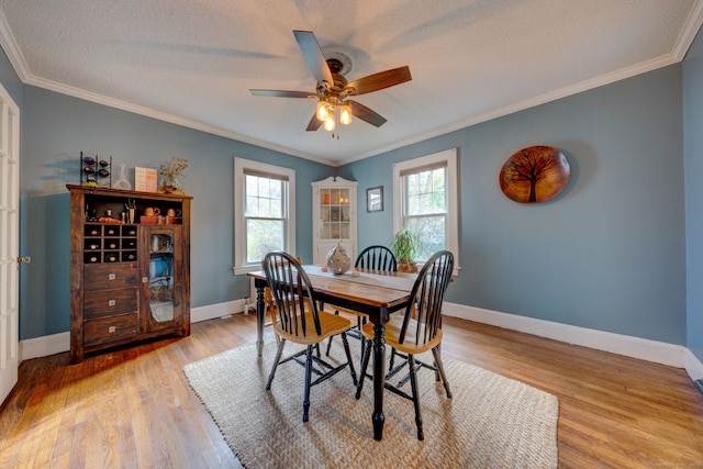 dining room with crown molding, baseboards, and light wood finished floors