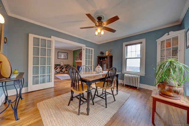 dining area featuring ornamental molding, wood finished floors, radiator heating unit, french doors, and baseboards