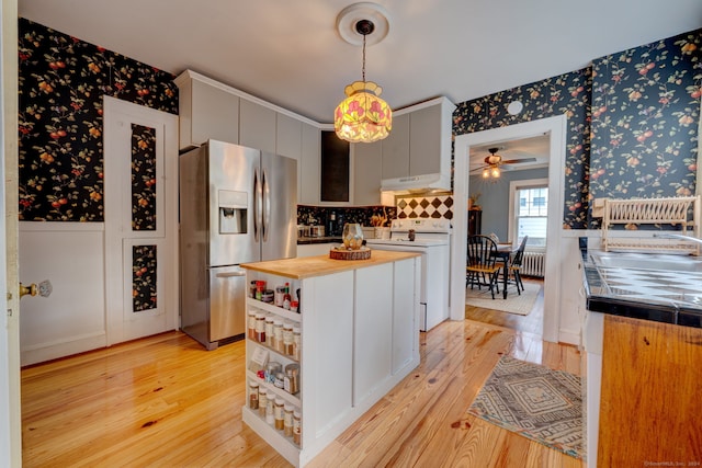 kitchen featuring white range with electric cooktop, under cabinet range hood, stainless steel fridge with ice dispenser, wallpapered walls, and wooden counters