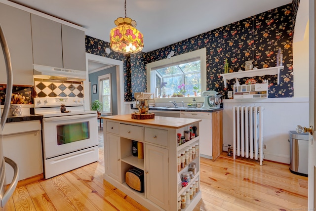 kitchen with under cabinet range hood, open shelves, radiator heating unit, white appliances, and wallpapered walls