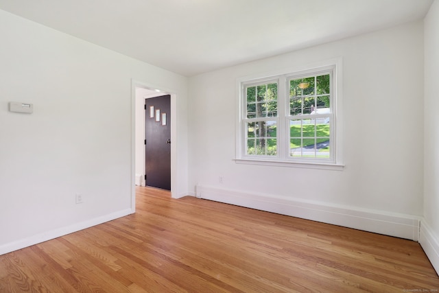 empty room with a baseboard radiator and light hardwood / wood-style flooring