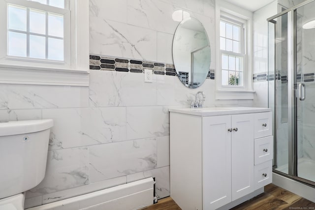 bathroom with a shower with door, wood-type flooring, toilet, tile walls, and vanity