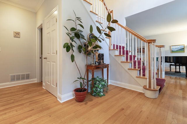 stairs featuring wood-type flooring and ornamental molding