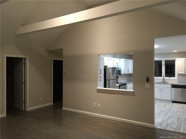 unfurnished living room with sink, high vaulted ceiling, beamed ceiling, and dark hardwood / wood-style floors