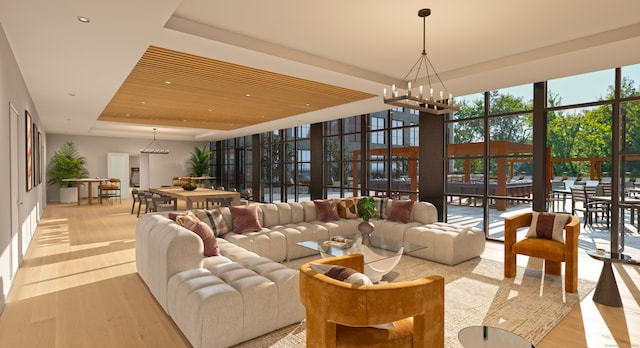 living room with a raised ceiling, floor to ceiling windows, a notable chandelier, light wood-type flooring, and a towering ceiling