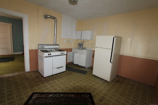 kitchen with washer / dryer, white appliances, and white cabinetry