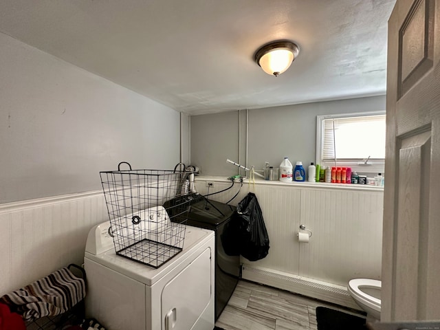 laundry area featuring washer and clothes dryer, baseboard heating, and light wood-type flooring